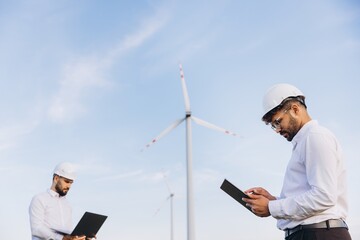 Engineers using laptop and tablet working in a wind turbine power plant