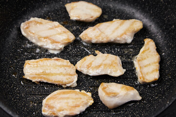 Grilled chicken pieces sizzling in a non-stick frying pan, showcasing golden-brown grill marks and juicy texture, perfect for culinary presentations and delicious meal ideas