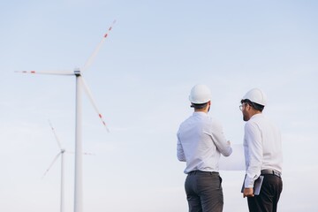 Engineers discussing blueprint at wind turbine power plant