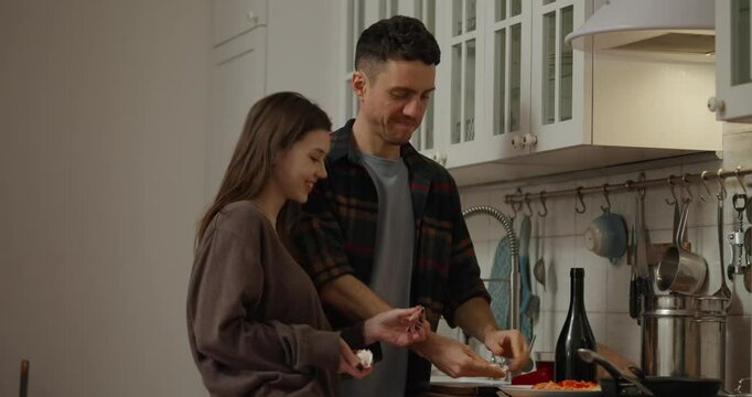 Guy and his girlfriend peel garlic while preparing a romantic dinner in a cozy kitchen at home in the evening. Guy and girl preparing romantic dinner in the evening