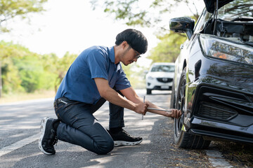 Mechanic or driver providing roadside assistance by changing a flat tire and performing minor...