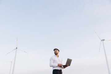 Arabian engineer working with laptop in a wind turbine power plant