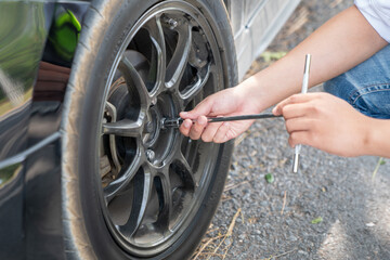 Mechanic or driver providing roadside assistance by changing a flat tire and performing minor...