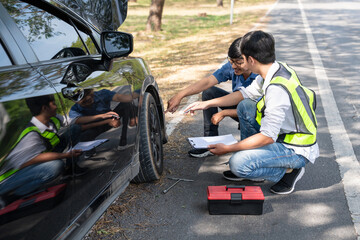 Mechanic or driver providing roadside assistance by changing a flat tire and performing minor...