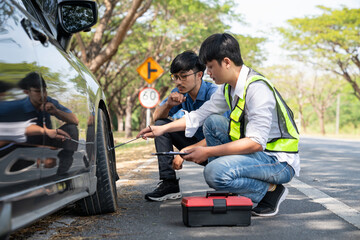 Mechanic or driver providing roadside assistance by changing a flat tire and performing minor...