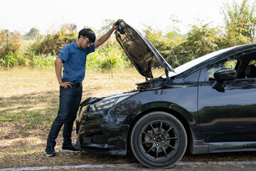 Naklejka premium Mechanic or driver providing roadside assistance by changing a flat tire and performing minor repairs on the side of the road during a vehicle breakdown.