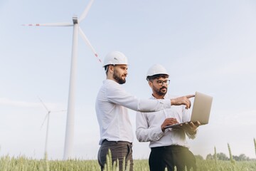 Engineers working on a laptop in a wind turbine field