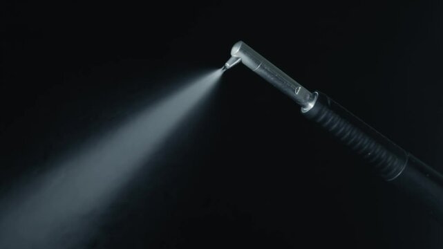 Dental Air abrasion with water spray, hydro abrasion or sandblasting teeth. High tech dental handpiece and water splash on dark background. dental hydro abrasion with water spray in slow motion video