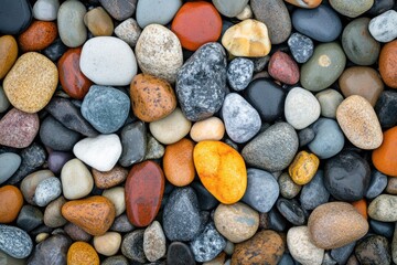 Close-up view of many small, colorful stones.  Various shades of  reds, oranges, yellows, grays, whites, and blacks.  Rounded shapes, densely packed
