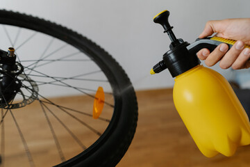 Close-up of mountain bike wheel getting cleaned with water sprayer, cyclist carefully wiping...
