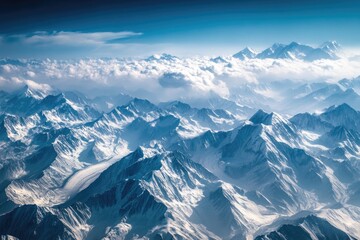 Aerial view of snow-capped Himalayan peaks.  Vast mountain ranges, cloud cover, and a clear blue sky