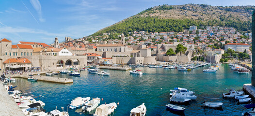 DUBROVNIK MARINA WITH BOATS AND THE OLD WALLS OF THE MEDIEVAL CITY - Croatian urban skyline -...