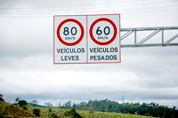 Sinalização rodoviária com limites de velocidade distintos para veículos leves (80 km/h) e...