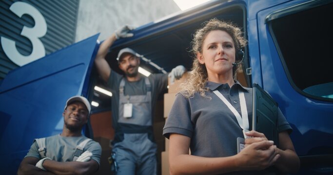 Team of Diverse Workers Standing Outside of Logistics Distribution Warehouse, Looking at Camera. Delivery Truck Full of Cardboard Boxes with Online Orders. Female Manager Holding Digital Tablet. - Powered by Adobe