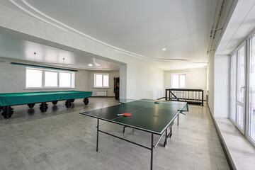 game room featuring a green ping pong table and a covered pool table. The room has a neutral...