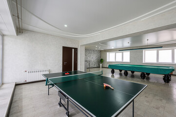 game room featuring a green ping pong table and a covered pool table. The room has a neutral...