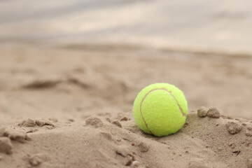 Yellow tennis ball lies on the sand. Sports and recreation concept, summer games. Tennis or...