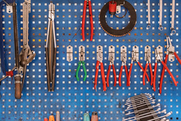 Wall-mounted tool set on pegboard in workshop. Old hand tools is displayed on perforated metal pegboard in a workshop setting. Use for themes related to maintenance and craftsmanship.