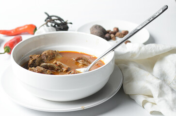 Overhead view of Nigerian goat pepper soup in a white soup plate, top view of goat meat pepper soup...