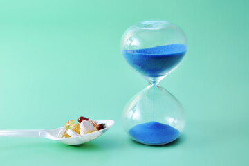 Hourglass and pills are next to each other, representing the concept of time and deadlines in people's lives.