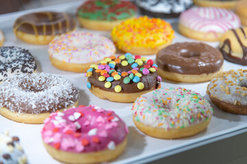 Assorted donuts displayed on a tray at a bakery during the morning rush