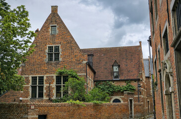 Leuven, Belgium: Historic red brick buildings, green shrubs, courtyard.

