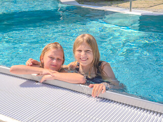 A group of joyful kids happily swimming together in a bright, sunny pool on a summer day
