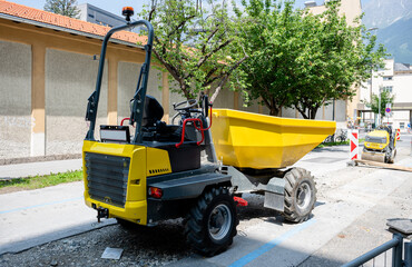 Yellow construction dumper truck parked on urban road during street work © AnastasiiaAkh