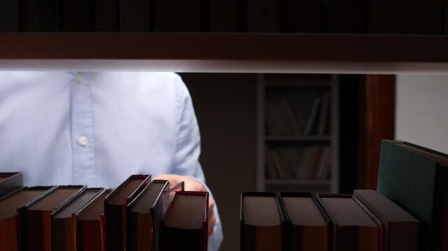 Librarian choosing book from bookshelf in library