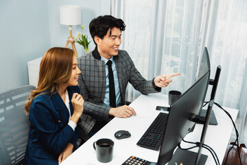 Business Asian coworkers analyzing marketing report project on two screen computer comparing value...