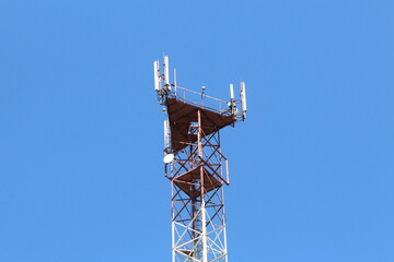Against the sky there is a pole with communication antennas.