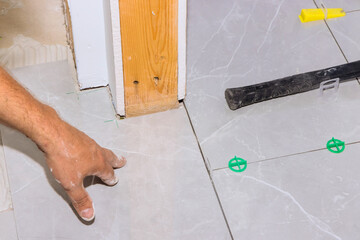 Hand of worker aligns tiles on floor while preparing for next step in home renovation.