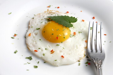 There is a fried egg with a fork on the plate.