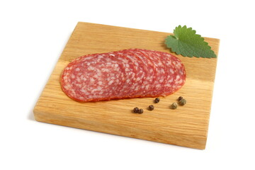 There are round pieces of salami on a wooden board.