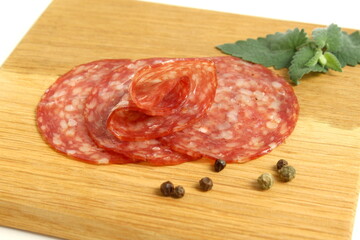 There are round pieces of salami on a wooden board.