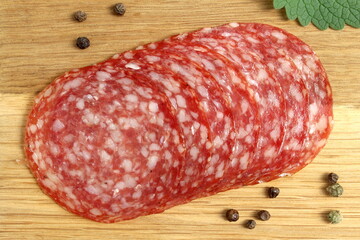 There are round pieces of salami on a wooden board.