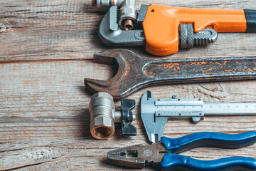 Variety of plumbing tools on wooden background. Copy space for text.