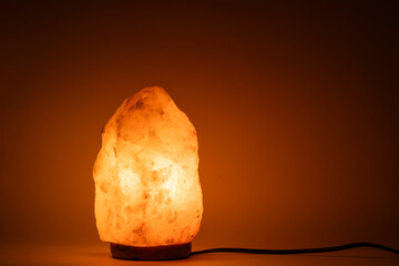 Salt lamp glows with warm bright orange light.