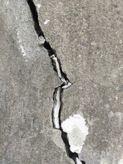 Deeply cracked grey concrete surface texture for construction defect analysis and distressed urban...