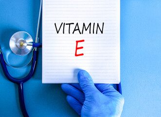 Vitamin E tocopherols symbol. Concept words Vitamin E on beautiful white note. Doctor's hand in...