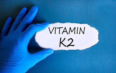 Vitamin K2 phylloquinone symbol. Concept words Vitamin K2 on beautiful paper. Doctor's hand in blue...
