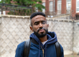 Young handsome African American man smoking cigarette in alley. Lips blowing smoke on blurred background. Portrait gangster smokes marijuana or cannabis. Portrait of a black guy smoking a cigarette.