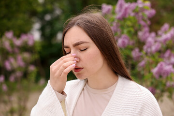 Woman suffering from seasonal pollen allergy near blossoming shrub on spring day