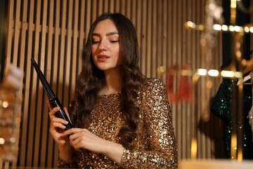 Woman curling her beautiful hair in dressing room