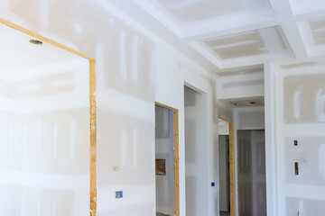 Freshly installed drywall is being prepared in modern home interior with unfinished surfaces open doorways.