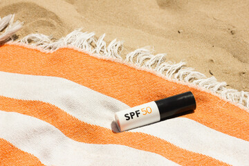 Mineral SPF50 sunscreen stick with UVA + UVB protection on the orange beach towel on the sand near...