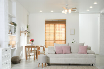 Stylish dining table with chairs and comfortable sofa in room. Interior design