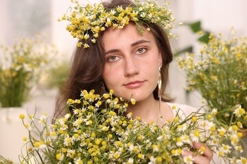 Portrait of beautiful woman with chamomile flowers indoors