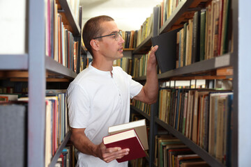 Man choosing book from shelf in public library