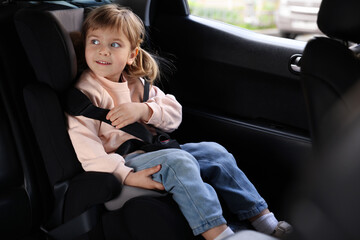 Little girl sitting in child safety seat inside car